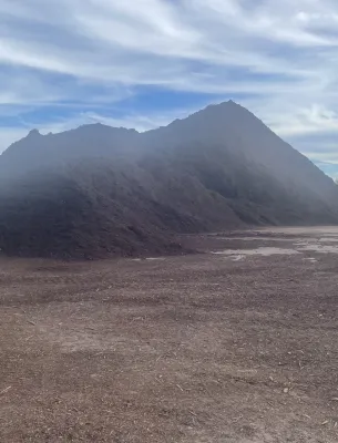 Large pile of dark soil under a cloudy sky
