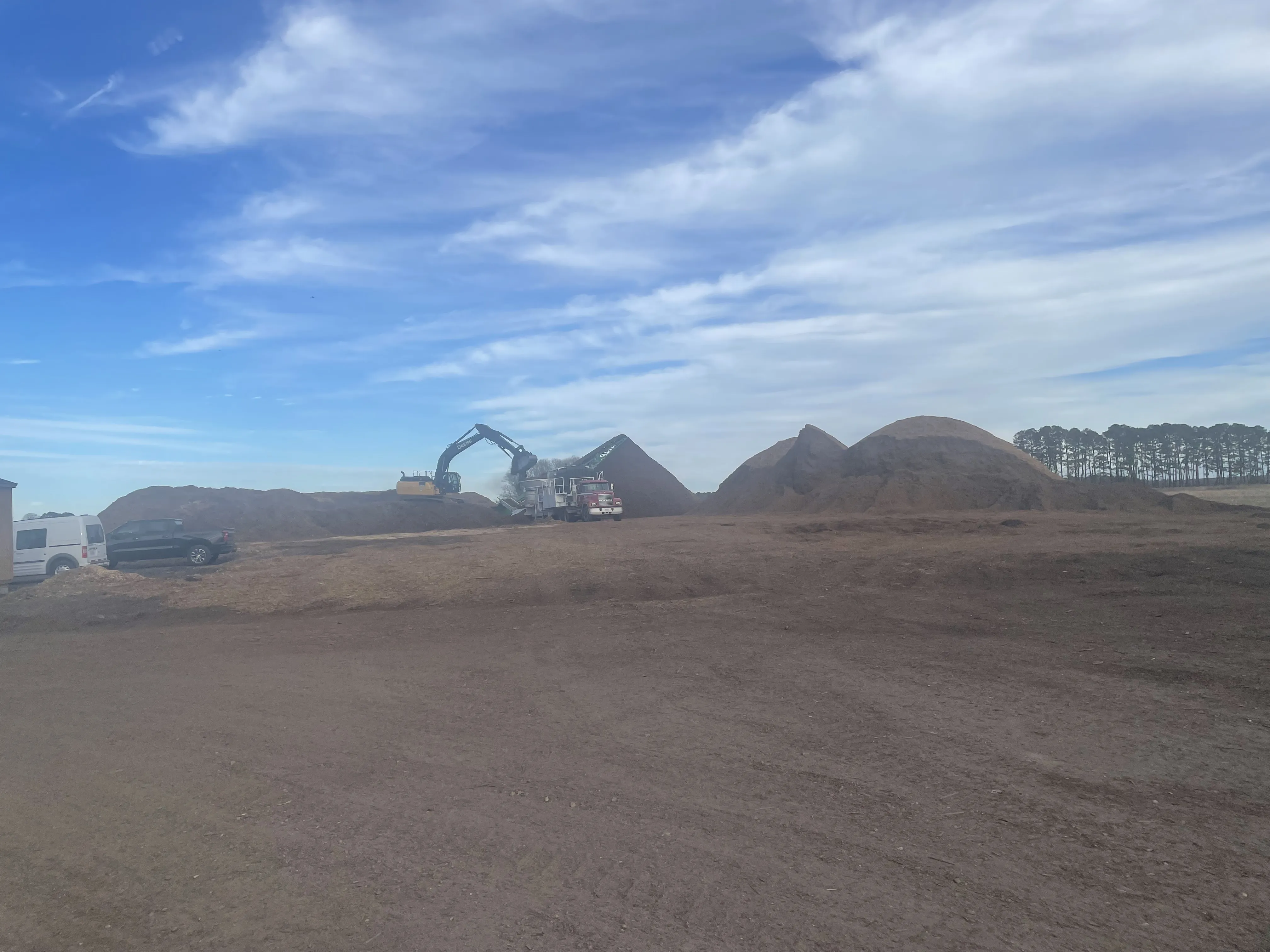 Excavator working with soil piles in an open field